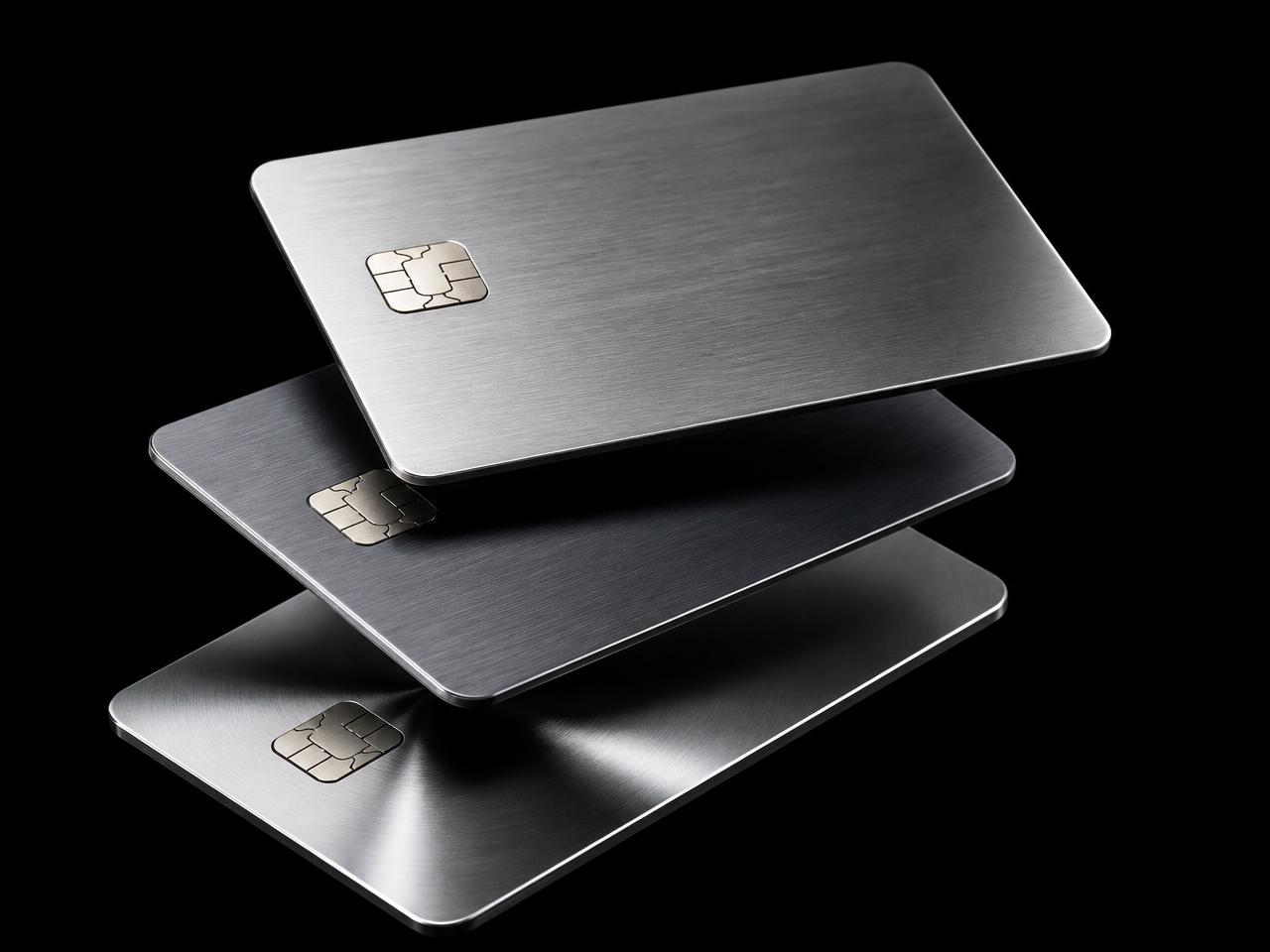 Brushed metal credit cards floating on a black background